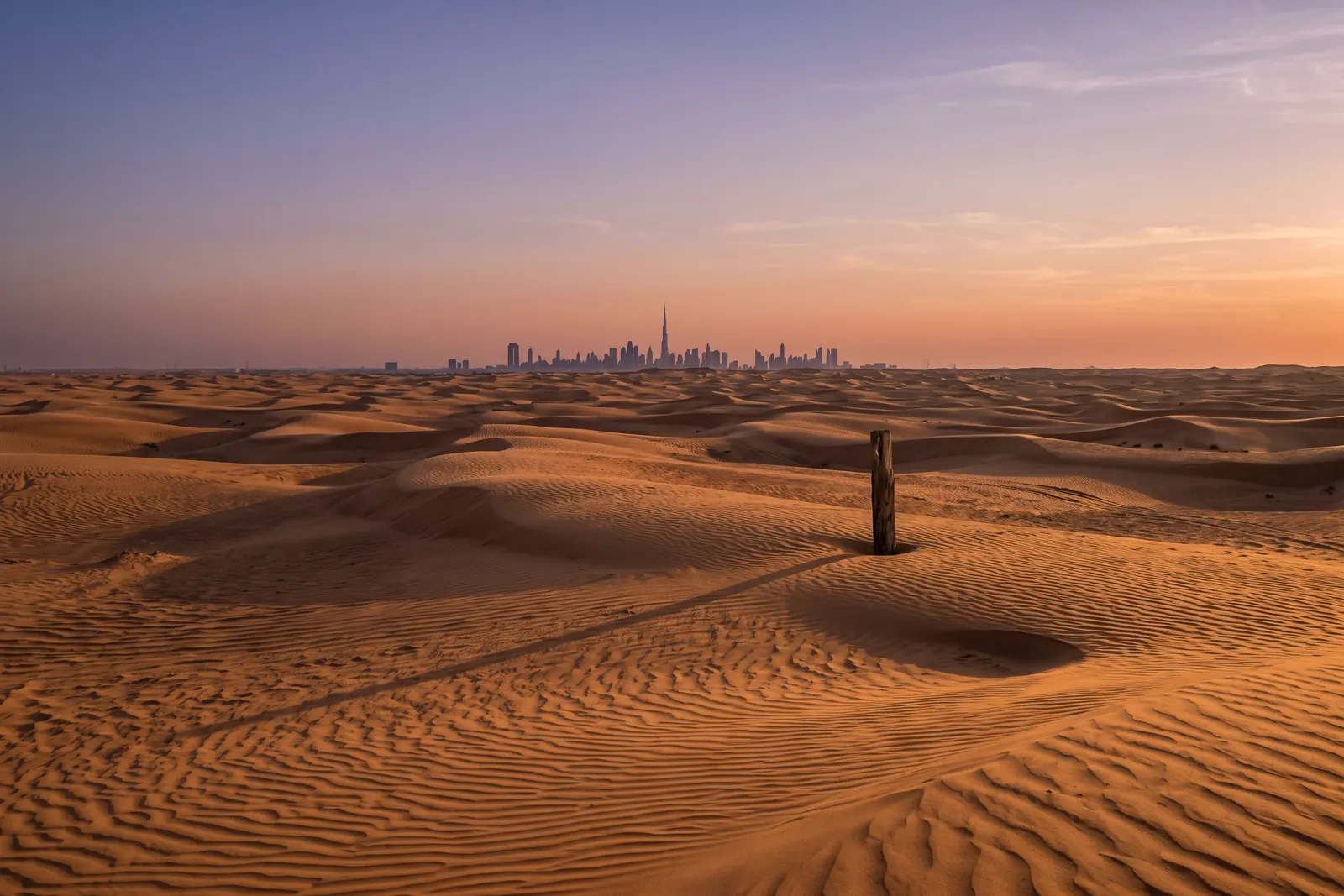 Dubai desert dunes at dusk with the city skyline on the horizon