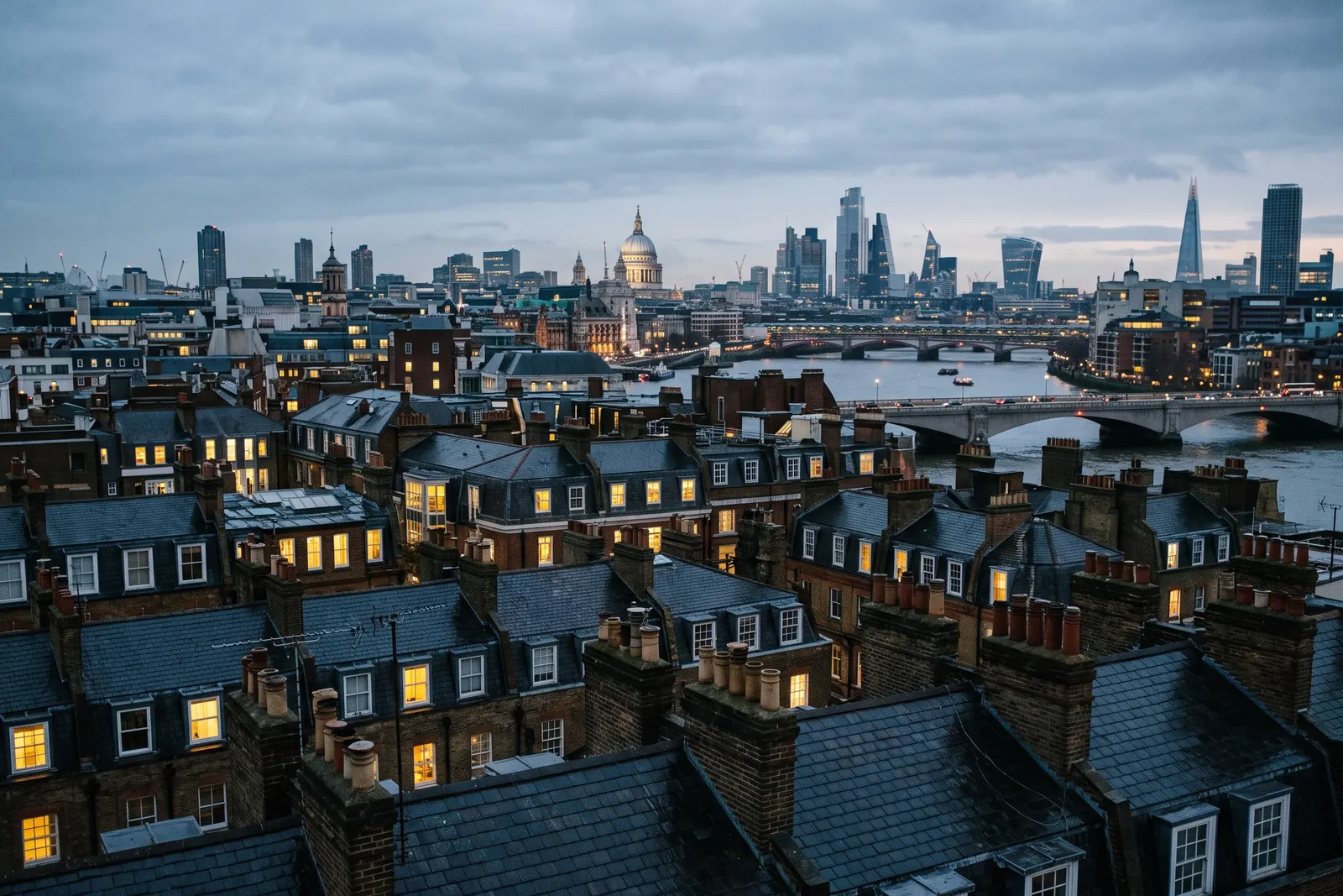 London rooftops at dusk with warm windows against a cool sky