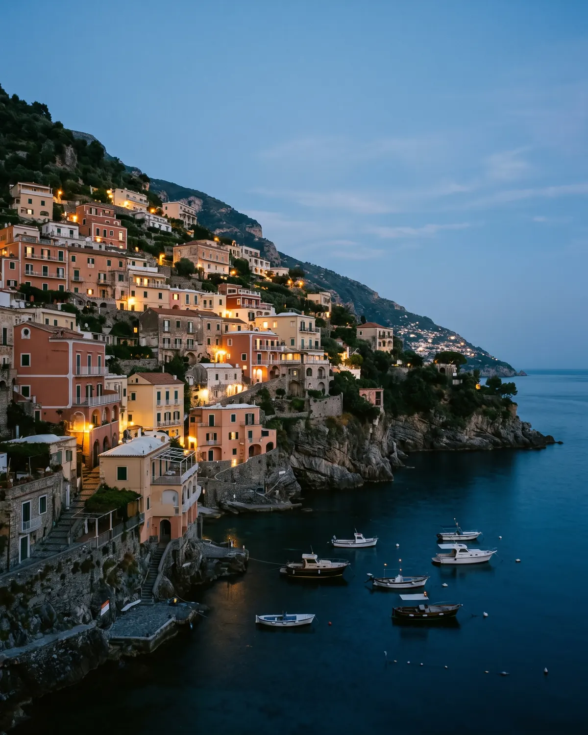 Positano at dusk, pastel houses stacked above a darkening sea